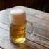 A pint of beer stands on a wooden table.