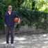 A man stands in a backyard with a basketball under his arm