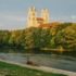 River with trees in the foreground, sunlit church in the background in Munich