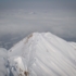 A snowy peak of the Alps over a cloud cover