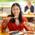 A woman in a beergarden in Munich eats a fish with chopsticks.