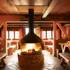 The interior of the restaurant at Schloss Elmau is made of wood with a fireplace in the middle.