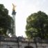 The golden statue of the Friedensengel statue stands among trees in the Bogenhausen district of Munich