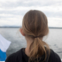 A girl looks out over a lake from an excursion boat.