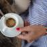 A woman with red nail polish holds a cup of espresso in a café in Munich.