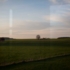 View from the train to wide fields in the evening sun.