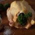 A chicken filled with parsley lies on a table.