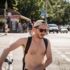 A man who is wearing swimming trunks is crossing the street at the Reichenbachkiosk in Munich.