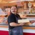 A salesman with a big piece of cheese in his hands at the weekly market at Hans-Mielich-Platz in Munich.