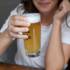 A woman in a white t-shirt in Munich holds a glass of beer in her hand.