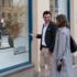 A man and a woman standing in front of a shop window