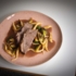 A meat dish with potato noodles and Brussels sprouts on a pink plate