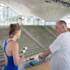 Two people standing on the 10-metre board in an indoor swimming pool