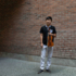 The musician Yusi Chen with his violin in front of a brick wall in Munich.