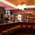 Bartender behind long counter, row of bar stools in foreground in bar Boilerman at 25hours hotel in Munich, Germany