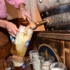 A man fills in beer in a jar from a wooden barrel
