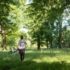 Young woman walks barefoot in summer through a park in Munich.