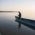 A fisherman in a little boat on Starnberger See takes a fish out of a net.