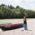 A woman is standing besides a canoe at the Isar River.