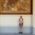 A man who is wearing swimming trunks is standing in front of a painting in Munich