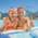 Two children in an outdoor pool, smiling at the camera and giving the thumbs up.