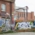 Graffiti on an old brick building and the adjacent wooden fence. In the background, a new brick building.