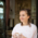 Young woman stands in the door of a café and drinks cappuccino in Munich.