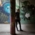 A woman stands in an underpass in front of a large mural in Munich.