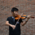 The musician Yusi Chen with his violin in front of a brick wall in Munich.