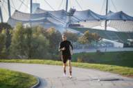 A woman in a sports outfit runs up the Olympic Hill in the Olympic Park in Munich.