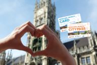 Due mani formano un cuore, sullo sfondo la torre del Municipio Nuovo in Marienplatz a Monaco di Baviera.