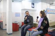 A man and a woman record a podcast in a laundromat.