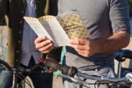 Un homme à vélo tient un prospectus de Munich à la main.