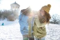 A woman and a man are joking on a sunny winter day in front of the Monopteros in the English Garden in Munich.