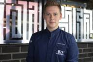 Michelin-starred chef Joshua Leise stands in his blue chef's jacket in the restaurant Mural in Munich.