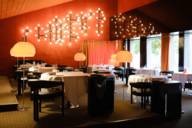 Vista interna del ristorante Tantris di Monaco di Baviera con i tipici interni anni '70 con grandi lampade da terra e pareti rosse.