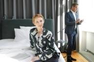 A woman is sitting on bed in a hotel in Munich. 