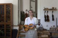 Violin maker Katharina Starzer stands in her workshop with a violin in her hands