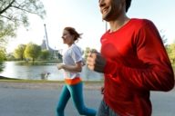 A woman and a man are jogging through the Olympic Park in Munich.