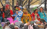 People in carnival costumes on an outdoor stage in driving snow.