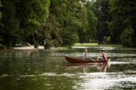A couple is sitting in a rowboat on the lake in the Englische Garten in Munich.