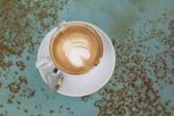 A cup of cappuccino stands on a turquoise table