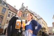 Young man with 'Maß' of beer and young woman with wheat beer in front of Hofbräuhaus in Munich