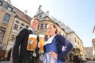 Young man with 'Maß' of beer and young woman with wheat beer in front of Hofbräuhaus in Munich