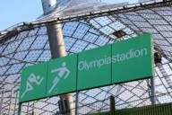 Green sign in Munich Olympic Stadium, tent roof in background