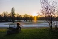 A woman sitting on a bench in the winter evening sun in the Olympic Park in Munich