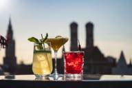 Cocktails on a rooftop terrace overlooking Munich and the silhouette of the city hall and Frauenkirche church