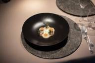 Nel ristorante Atelier del Bayerischer Hof c'è un piatto nero con una pietanza sul tavolo.