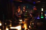 A singer, a guitarist and a cello player make music in a bar in Munich.
