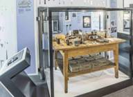 Tavolo di legno con numerosi strumenti di laboratorio in una teca di vetro.